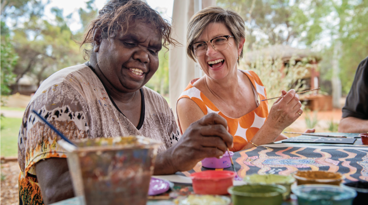 Two women painting at a table outside