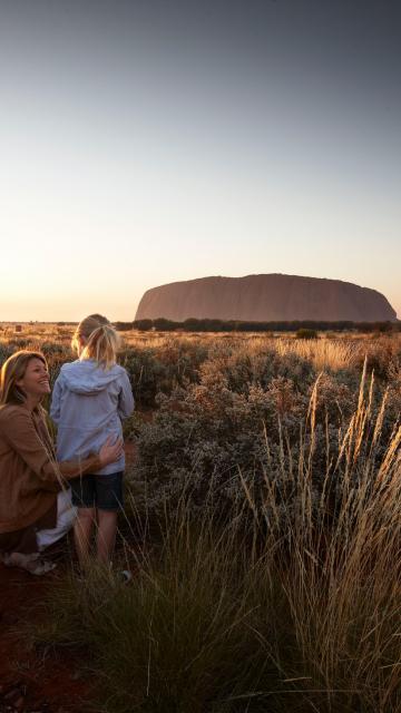 A family looking at Ayer's Rock at sunset